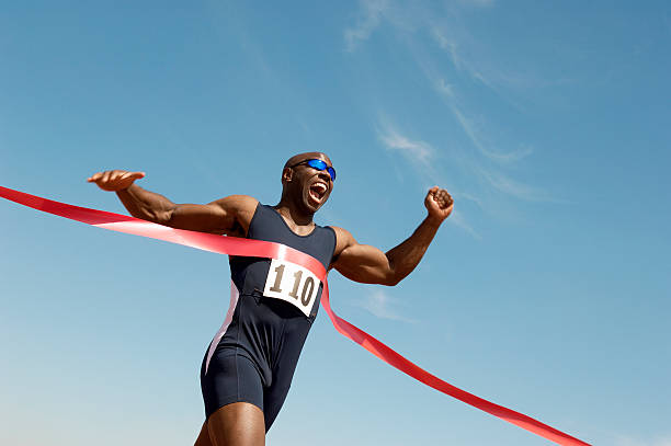 corredor romper la cinta de finish line - posición deportiva fotografías e imágenes de stock