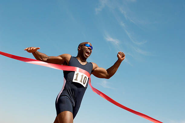 runner breaking finish line tape - sportrace stockfoto's en -beelden