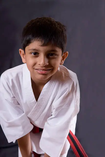 A young boy poses for the camera in a martial arts uniform.