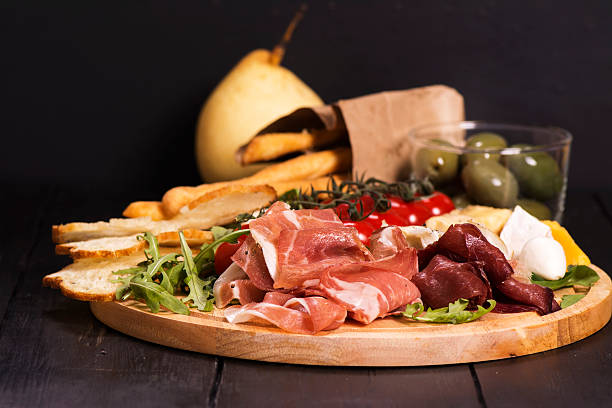 diferentes tipos de aperitivos italianos: jamón, queso, grissini, aceitunas, frutas - antipasto fotografías e imágenes de stock