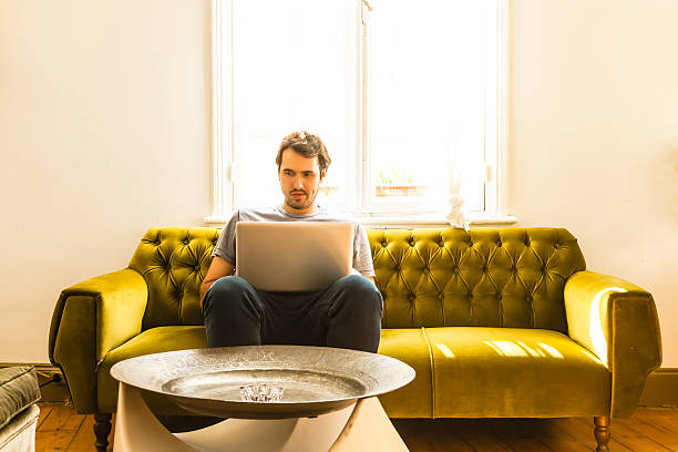 istock Guy working on laptop indoor sitting on a sofa 530920711