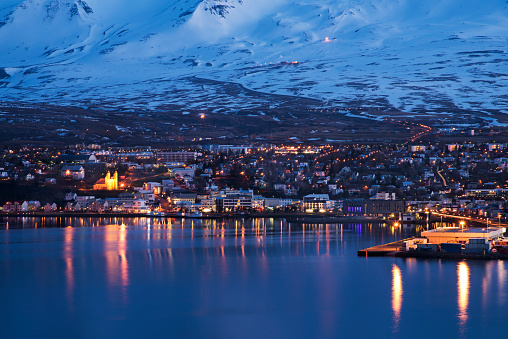 A late evening view of the city centre of Akureyri in Northern Iceland from across the fjord water. The main cathedral, shopping streets, industrial docks and private housing can be seen, Akureyri, Iceland