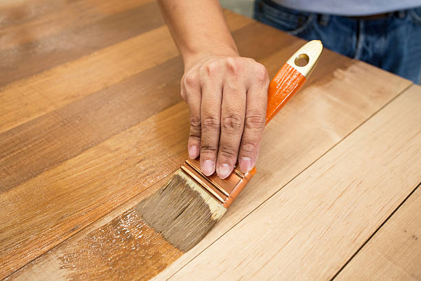 application de vernis de protection sur un mobilier en bois - varnishing hardwood decking photos et images de collection