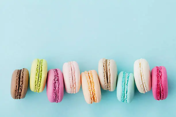 Cake macaron or macaroon on turquoise background from above, colorful almond cookies, pastel colors, vintage card, top view