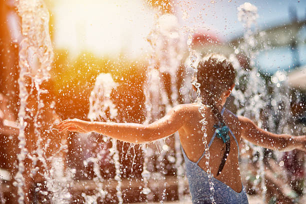 Little girl having fun in water park fountain Little girl having fun jumping, dancing and spinning in water park fountain. Water is splashing everywhere. Summer sun shining brightly. drinking fountain stock pictures, royalty-free photos & images