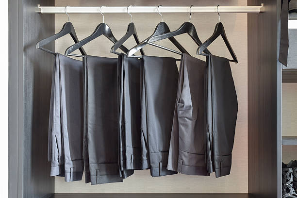 row of black pants hangs in wardrobe at home