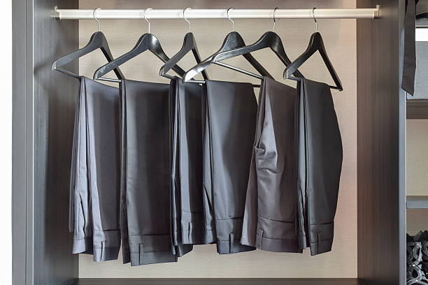 row of black pants hangs in wardrobe at home stock photo