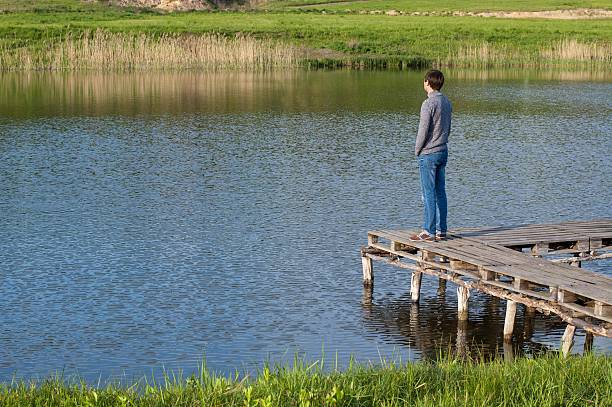 istock Man standing on the pier of a pond 530931454