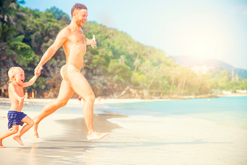 Father and son running along beach.