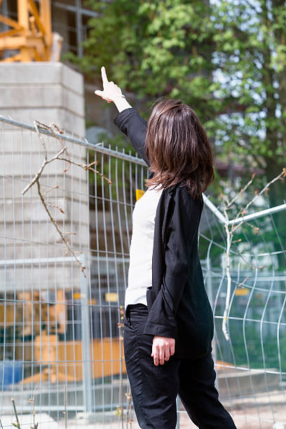 istock woman standing at construction site and pointing at building 530932116