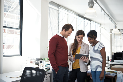 Shot of three designers discussing something on a tablet