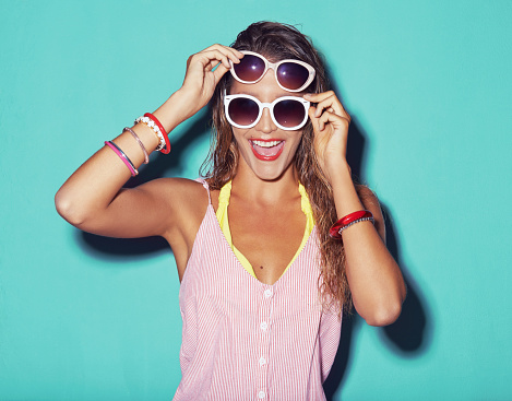 Shot of a young woman wearing sunglasses against a colourful background