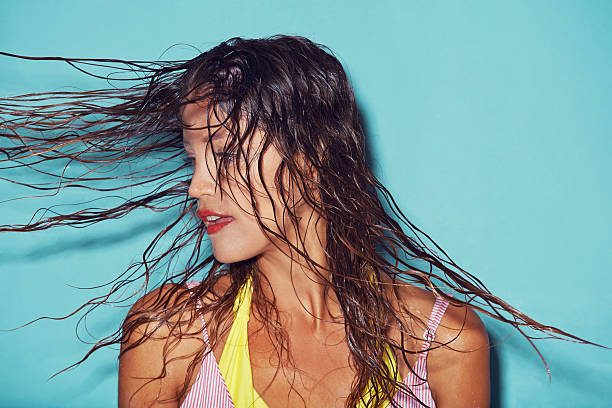 There's just something about wet hair... Shot of a young woman flipping her wet hair against a blue background wet hair stock pictures, royalty-free photos & images