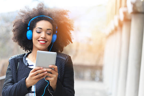istock Smiling young woman with headphones using digital tablet 530935696