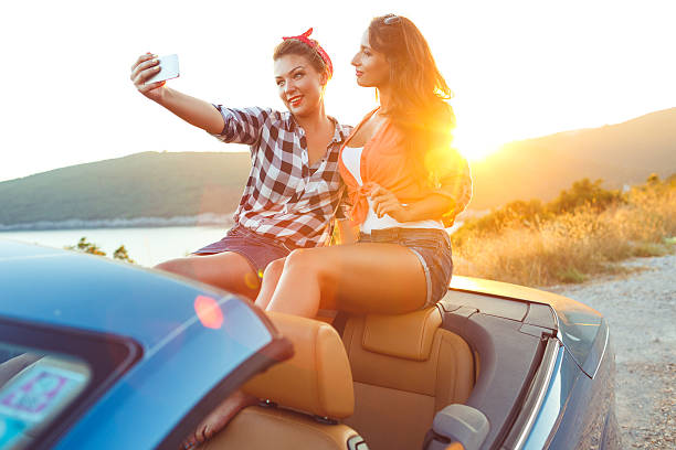 istock Two young beautiful girls are doing selfie in a convertible 530936384