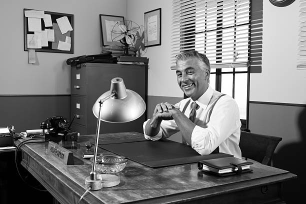 istock Smiling vintage director sitting at office desk 530936774