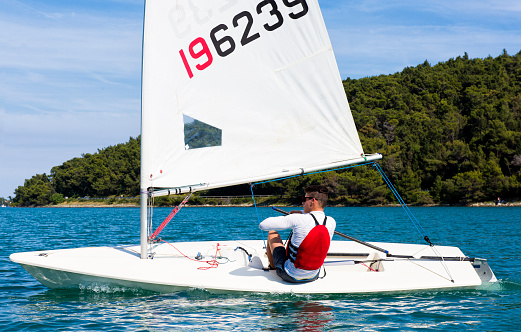 Side view of young male boats-man sailing on laser class sailing boat