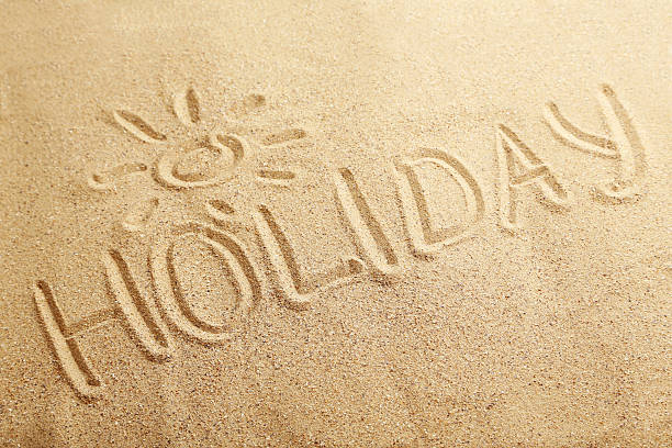 istock Holiday handwritten in a beach sand 530939278