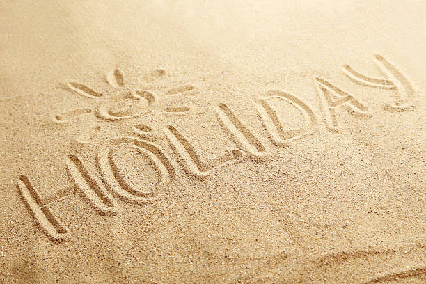 istock Holiday handwritten in a beach sand 530939358