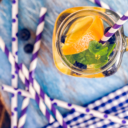 Infused water with fresh blueberries, oranges and mint served in a glass jar.