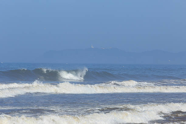 Distant Byron Bay A photograph of Byron Bay in Australia taken from Brunswick Heads Beach. Breaking waves can be seen in the foreground and the Byron Bay Lighthouse in the distance. brunswick heads nsw stock pictures, royalty-free photos & images