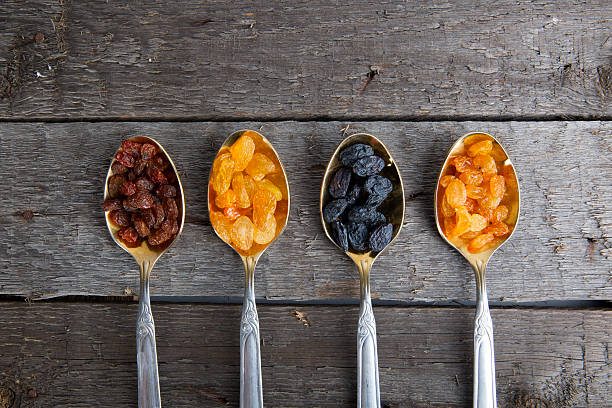 istock Raisins in metal spoons on wooden table 530940646