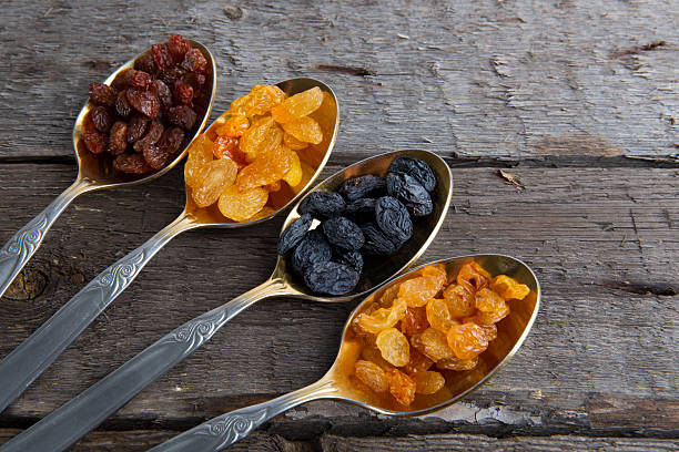 istock Raisins in metal spoons on wooden table 530941124