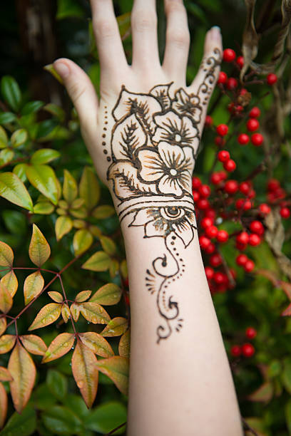 Wet henna tatoo on hand and arm natural light henna tatoo with flora and fauna in the background wrist tattoo stock pictures, royalty-free photos & images