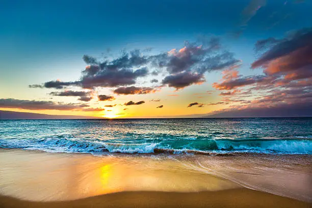 Sunset at the Kaanapali Beach on the west shore of the island of Maui in Hawaii with the island of Lanai and Molokai in the background. A beautiful sandy beach, a popular tourists destination in Hawaii. Photographed in horizontal format on location in Maui Hawaii.