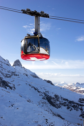 Mount Titlis-Engelberg, Canton of Obwalden, Switzerland - November 23, 2014: The Titlis Rotair gondola carrying skiers, snowboarders and tourists up to the summit of Titlis at 3,020 metres above sea-level. The cable car revolves 360 degrees during the five-minute trip with beautiful snow-covered mountain peaks views.  