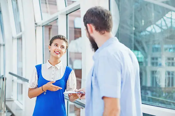 Photo of Beautiful young flight attendant checking documents of male tourist