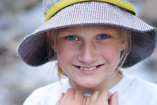 Cute Young Girl Smiling and Wearing Hat - Smiling girl showing off fashionable hat.  Focus on eyes with smooth bokeh.