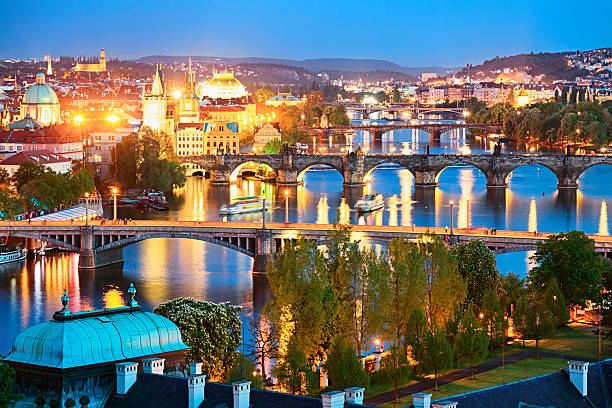 Night view of Church of St Nicholas in Prague old town with illuminated baroque dome and historic rooftops. g.