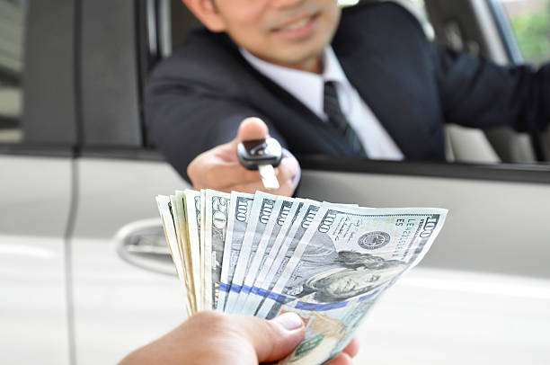 Businessman giving a car key exchanging with money Businessman giving a car key exchanging with money - car ( auto) pawn concept cash for cars stock pictures, royalty-free photos & images