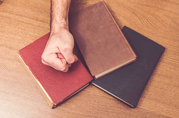 istock Man's hand hitting on some books on a table 530970261