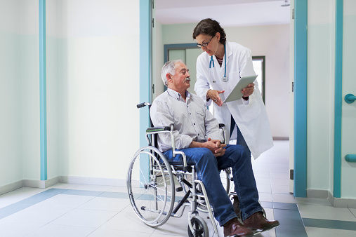 Doctor is chatting with a patient on a wheelchair. More files of this series and models on port.