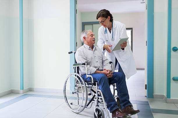 Doctor helping a patient Doctor is chatting with a patient on a wheelchair. More files of this series and models on port. demobilization photos stock pictures, royalty-free photos & images