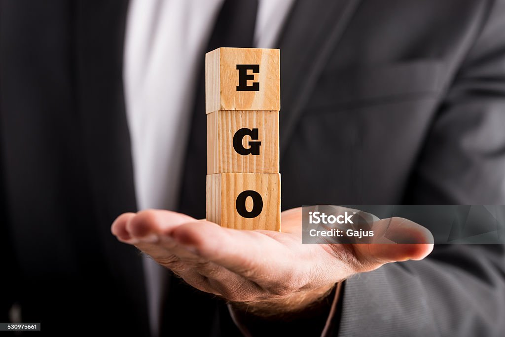 Businessman holding wooden alphabet blocks reading - Ego Businessman holding wooden alphabet blocks reading - Ego - balanced in the palm of his hand in a conceptual image. Vanity Stock Photo