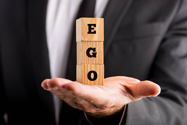 Businessman holding wooden alphabet blocks reading - Ego Businessman holding wooden alphabet blocks reading - Ego - balanced in the palm of his hand in a conceptual image. showing off stock pictures, royalty-free photos & images