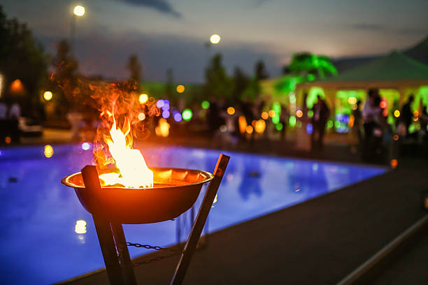 Flaming torch at sunset by the pool Flaming torch at sunset by the pool at wedding reception luau stock pictures, royalty-free photos & images