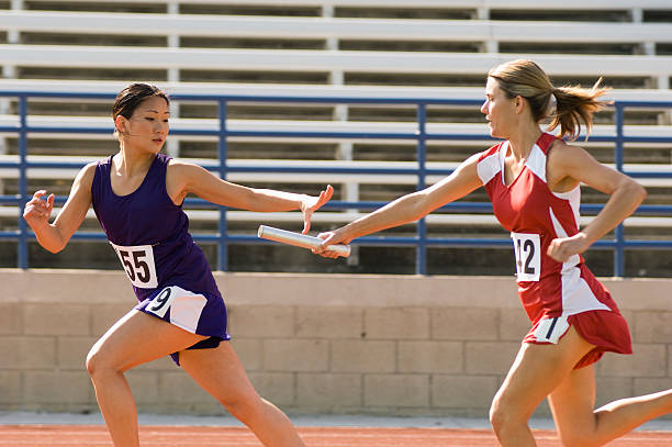 Female track athlete passing relay baton