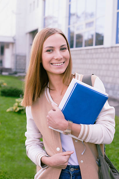 istock Student standing with book in her hands and laughing 530981451
