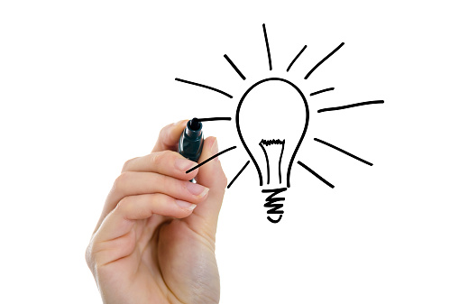 Hand of a businesswoman drawing Lightbulb on a virtual whiteboard.