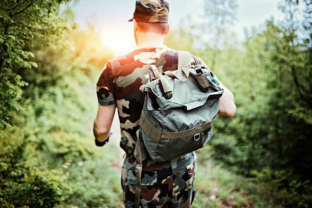 Soldier with backpack Soldier on the forest, caries a backpack. Watching the territory. Rear view. body adornment rear view young men men stock pictures, royalty-free photos & images