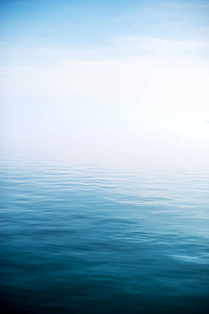 Calm and deep blue lake High contrast image of small ripples and waves of a calm, deep lake with foggy horizon horizon over water stock pictures, royalty-free photos & images