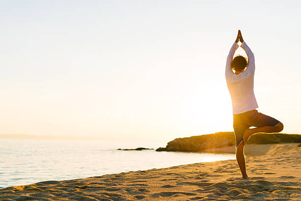 istock Practicing yoga and meditation in summer on beach in sunset 530990360