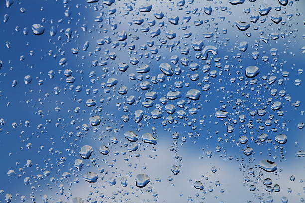 istock Rain drops on window with blue cloudy sky in background 530991792