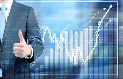 Success concept with businessman showing thumbs up next to business chart
