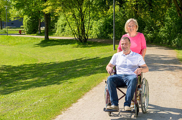 istock Man seated in wheel chair while wife pushes 530998718