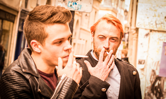 Two friends smoking alongside the streets of Paris, France.
